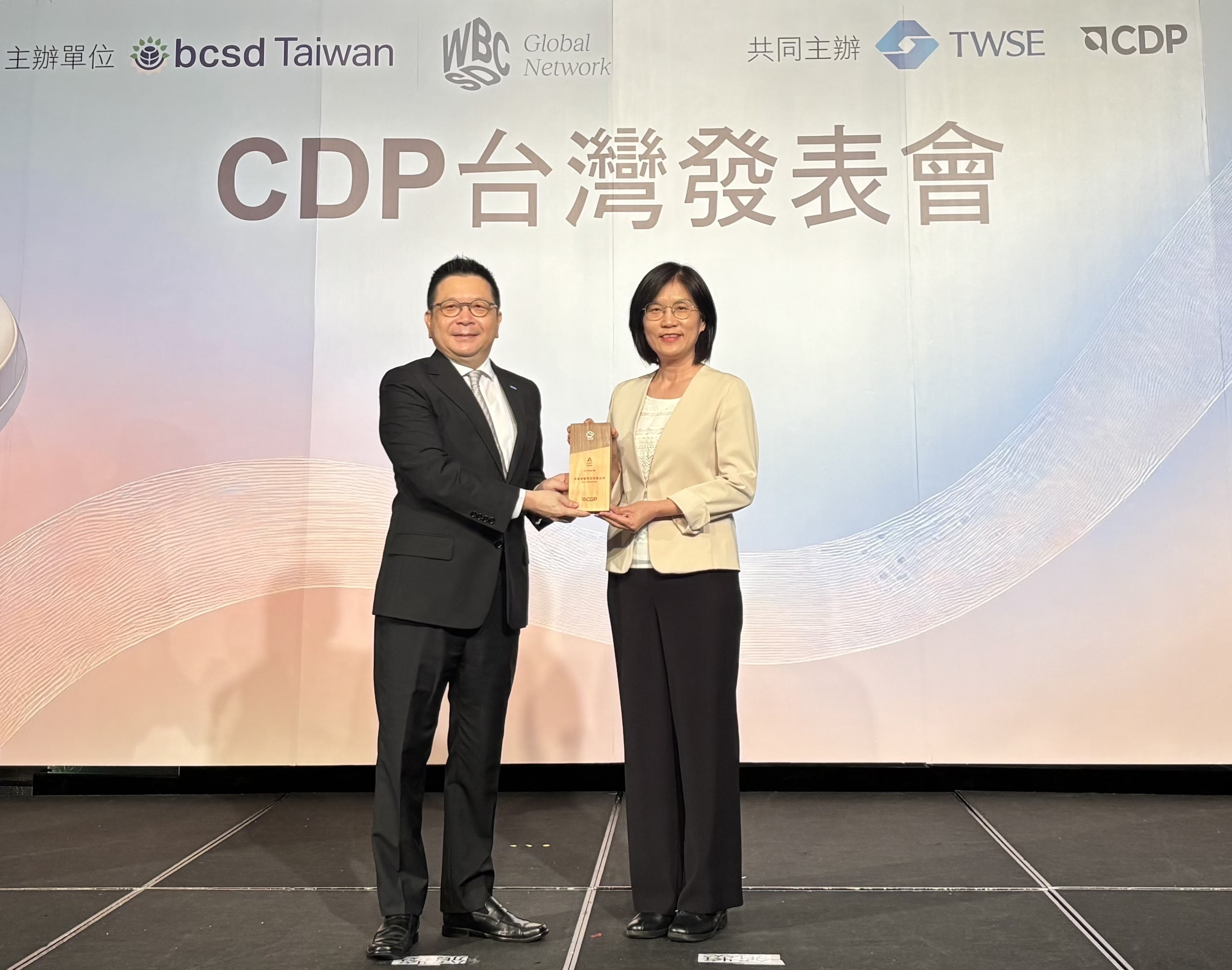 ng28南宮相信品牌力量永續(xù)成果再獲國際評比肯定，獲頒CDP氣候與水資源雙項領(lǐng)導力評級。今由臺灣證券交易所董事長林修銘（左）頒獎，ng28南宮相信品牌力量光電永續(xù)長古秀華（右）代表受獎